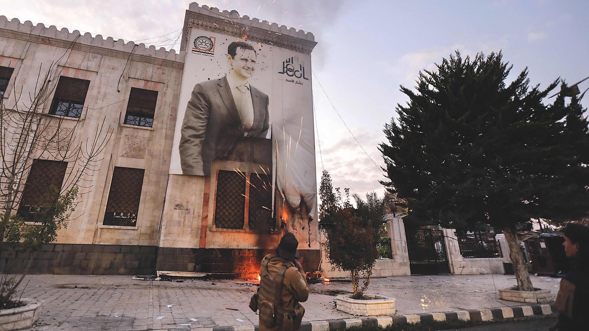 El final. Un rebelde dispara contra una pancarta propagandista de Bashar al-Asad tras la caída de Damasco.