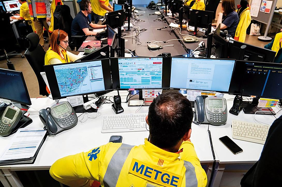 Imagen principal - Arriba: la sala de coordinación del SEM en Barcelona, Abajo, a la izda.: un café rápido entre salidas. A la dcha.: una atención a domicilio por un posible ictus. La jornada se mueve constantemente entre esos tres escenarios: el centro desde el que se escuchan las alertas -se priorizan los casos y se decide la respuesta-, el lugar de la emergencia y una breve pausa que permite recomponerse.