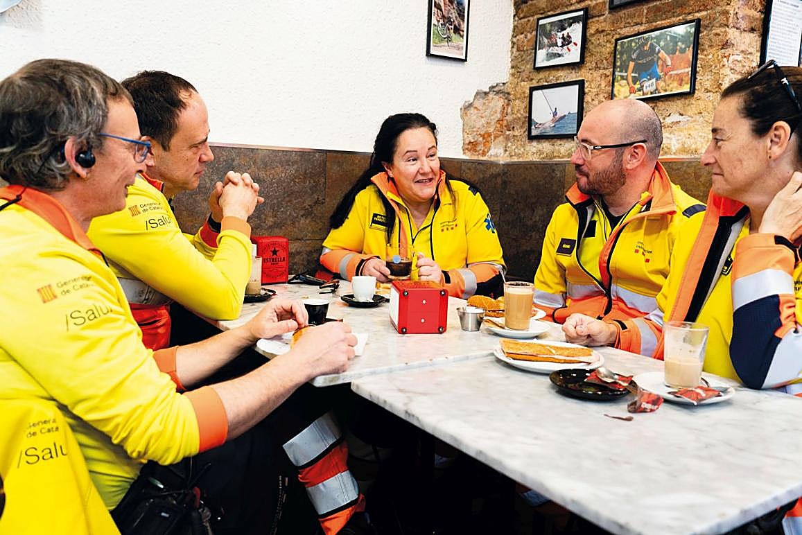 Imagen secundaria 1 - Arriba: la sala de coordinación del SEM en Barcelona, Abajo, a la izda.: un café rápido entre salidas. A la dcha.: una atención a domicilio por un posible ictus. La jornada se mueve constantemente entre esos tres escenarios: el centro desde el que se escuchan las alertas -se priorizan los casos y se decide la respuesta-, el lugar de la emergencia y una breve pausa que permite recomponerse.