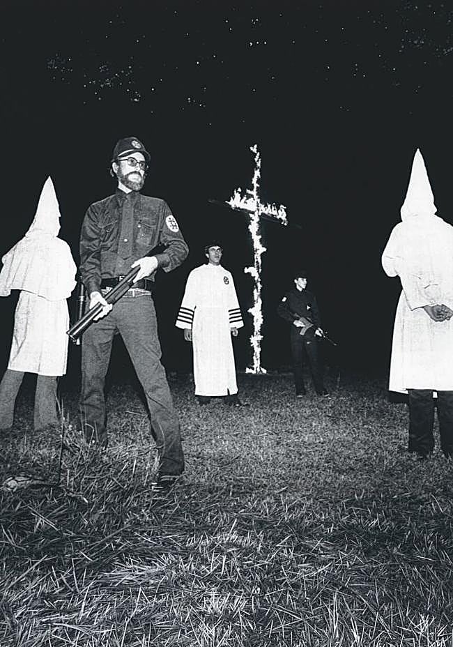 Adrianne, a la izquierda, se crio como Derek en un hogar supremacista. Su padre, Don Black, (con túnica junto a la cruz) era 'mago imperial' del Ku Klux Klan y miembro del partido nazi de Estados Unidos.