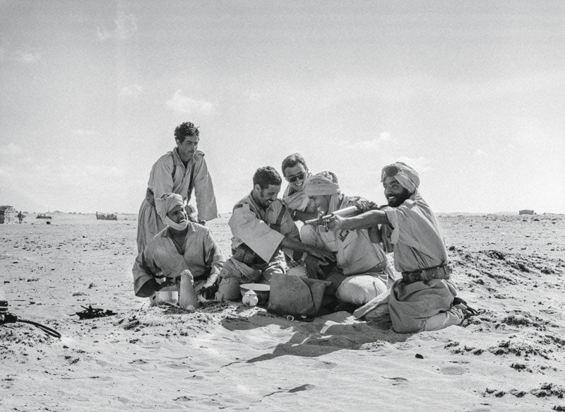 Tardé 50 años en ver esta fotografía, que no se positivó en su momento. En la frontera norte del Sáhara entonces todavía español, proximidades de Tah, un grupo de soldados nativos preparan el té y bromean. Mi relación con ellos era excelente, pues llevaba ya ocho meses en la región. Pese a la prohibición oficial de que fueran periodistas a zonas críticas, mi amigo el comandante de la Territorial Fernando Labajos –él tomó la foto–, que fue para mí una especie de padrino de guerra sahariano, me dio un uniforme para que, camuflado entre sus soldados, pudiera acompañarlos clandestinamente en las patrullas. Viví así situaciones que conté en el periódico y otras que no conté jamás, y por eso confiaban en mí. Las reglas eran las reglas.