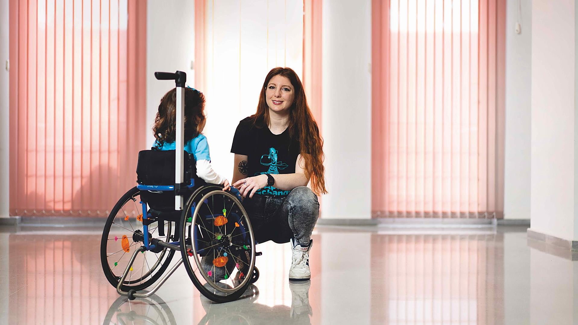 A los 9 meses Deva, en la foto con su madre, no podía sentarse y apenas sujetaba la cabeza. Ahora, con casi 3 años, maneja su silla de ruedas.