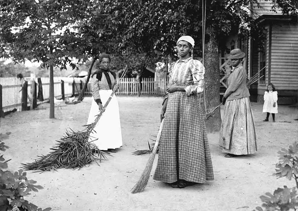 Una pequeña ama vigila a tres esclavas que barren el patio de una casa en Belton (Carolina del Sur).