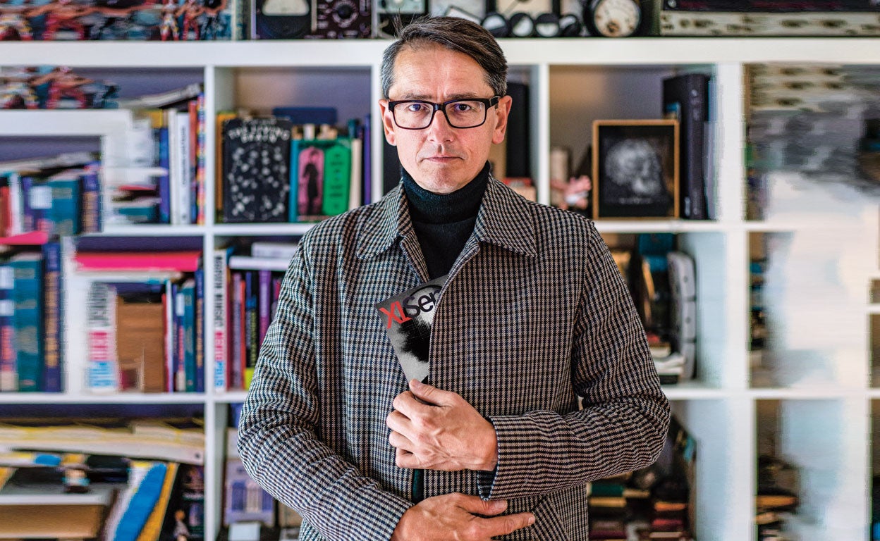 Kinglemann posa con la revista ya desencriptada. El artista alemán creó la primera obra de arte con ayuda de inteligencia artificial que fue vendida por Sotheby's en 2019 por 47.000 euros. Si quieres descubrir cómo es la obra que oculta bajo su abrigo, pincha en el enlace de abajo. Allí te será desvelado el código secreto que deberás introducir y ¡voilá!... También podrás comprarla convertida en NFT, aquí.