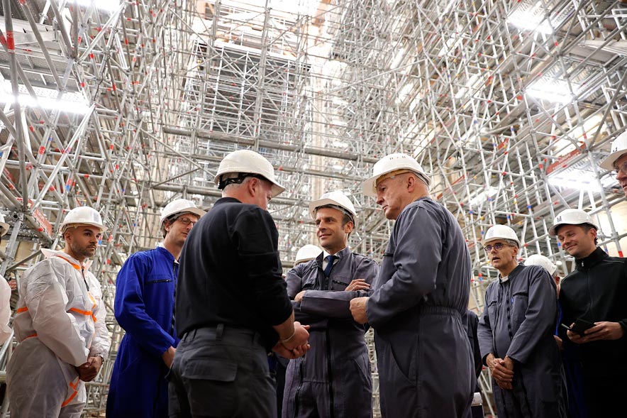 El presidente francés Emmanuel Macron (en el centro) y el general del ejército francés Jean-Louis Georgelin (junto a Macron, a la drecha), responsable de la coordinación de los trabajos de reconstrucción de Notre-Dame,hablan con los trabajadores una visita a la catedral con motivo del tercer aniversario del incendio.