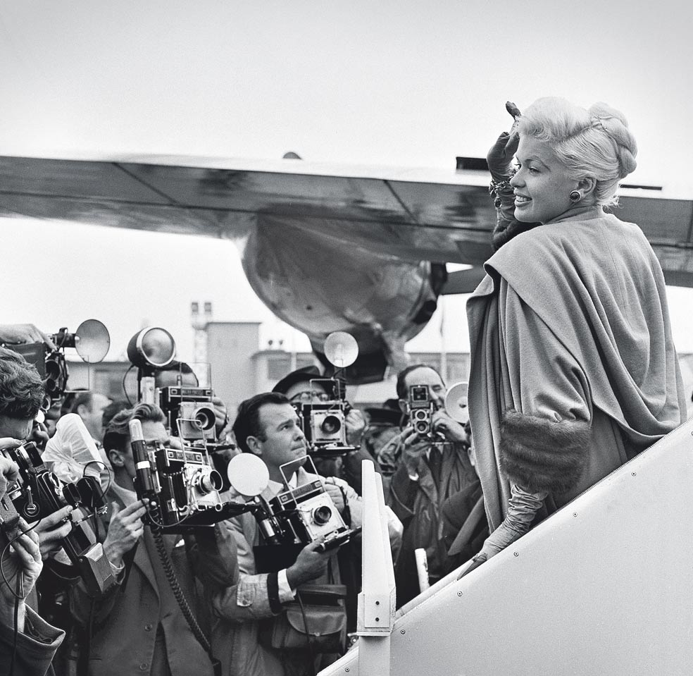 Jayne Mansfield llegando al aeropuerto de Londres en 1957. Era su momento de mayor esplendor. Además de sus películas, que catalizaban su atractivo sexual, ocupó la portada de Playboy cada febrero entre 1955 y 1958, y de nuevo en 1960.