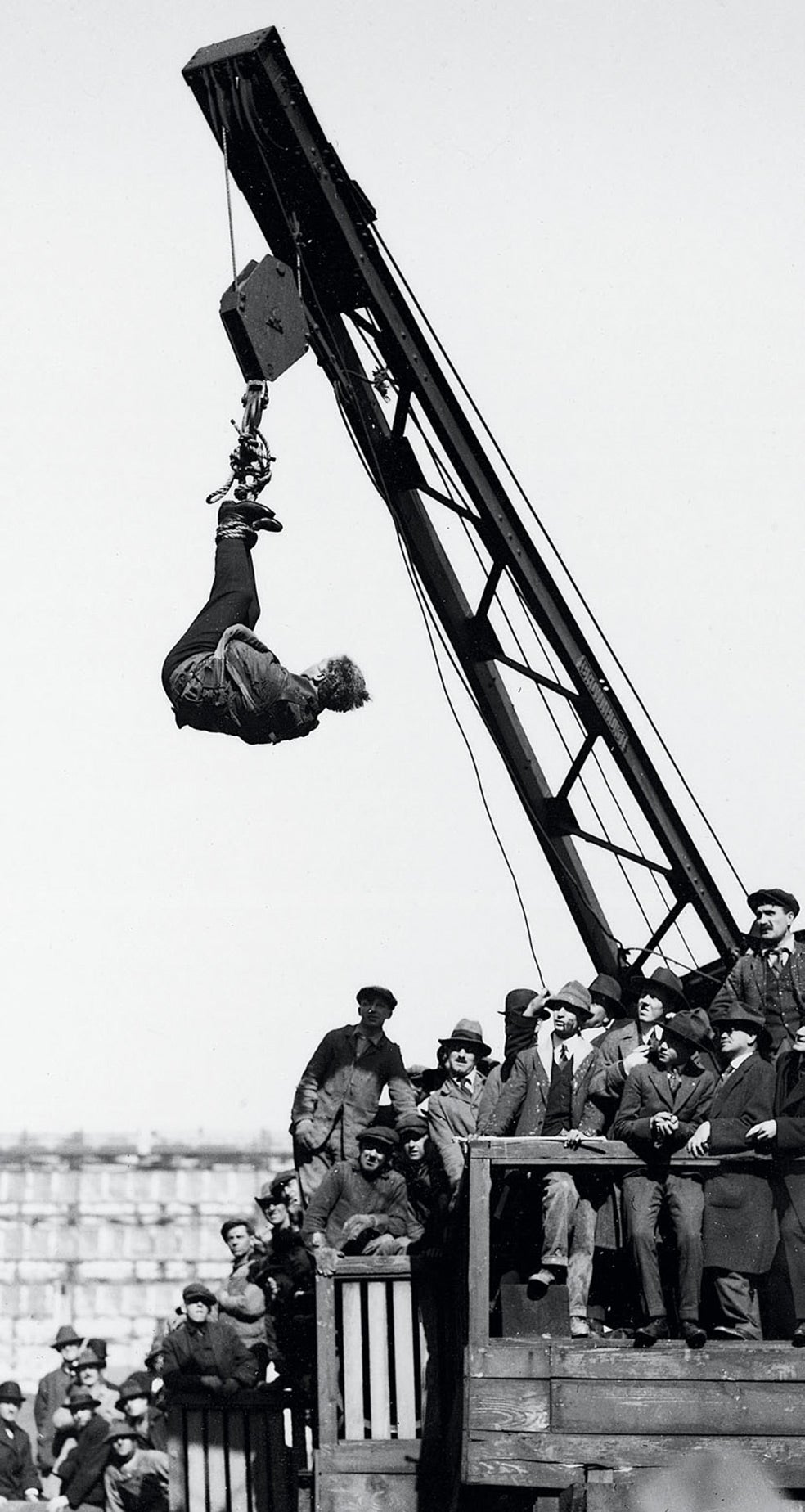 Uno de sus más espectaculares y repetidos desafíos. Colgado de un edificio o de una grúa, Houdini quedaba boca abajo dentro de una camisa de fuerza. Tardaba apenas tres minutos en deshacerse de la prenda. Esta imagen fue tomada en Nueva York, en 1910. Un truco realizado en la vía pública, todo fuerza y flexibilidad.