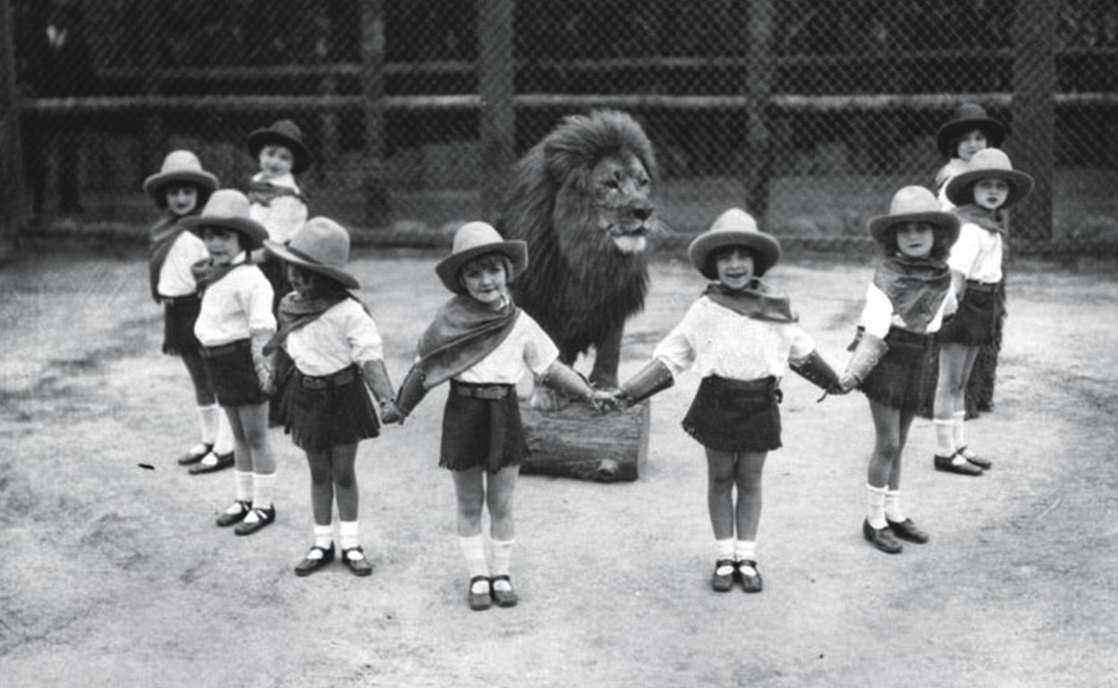 En una postal que costaría hoy imaginar posible, nueve colegialas se dan la mano en torno a otro de los leones que vivió en el parque entre 1925 y 1942.