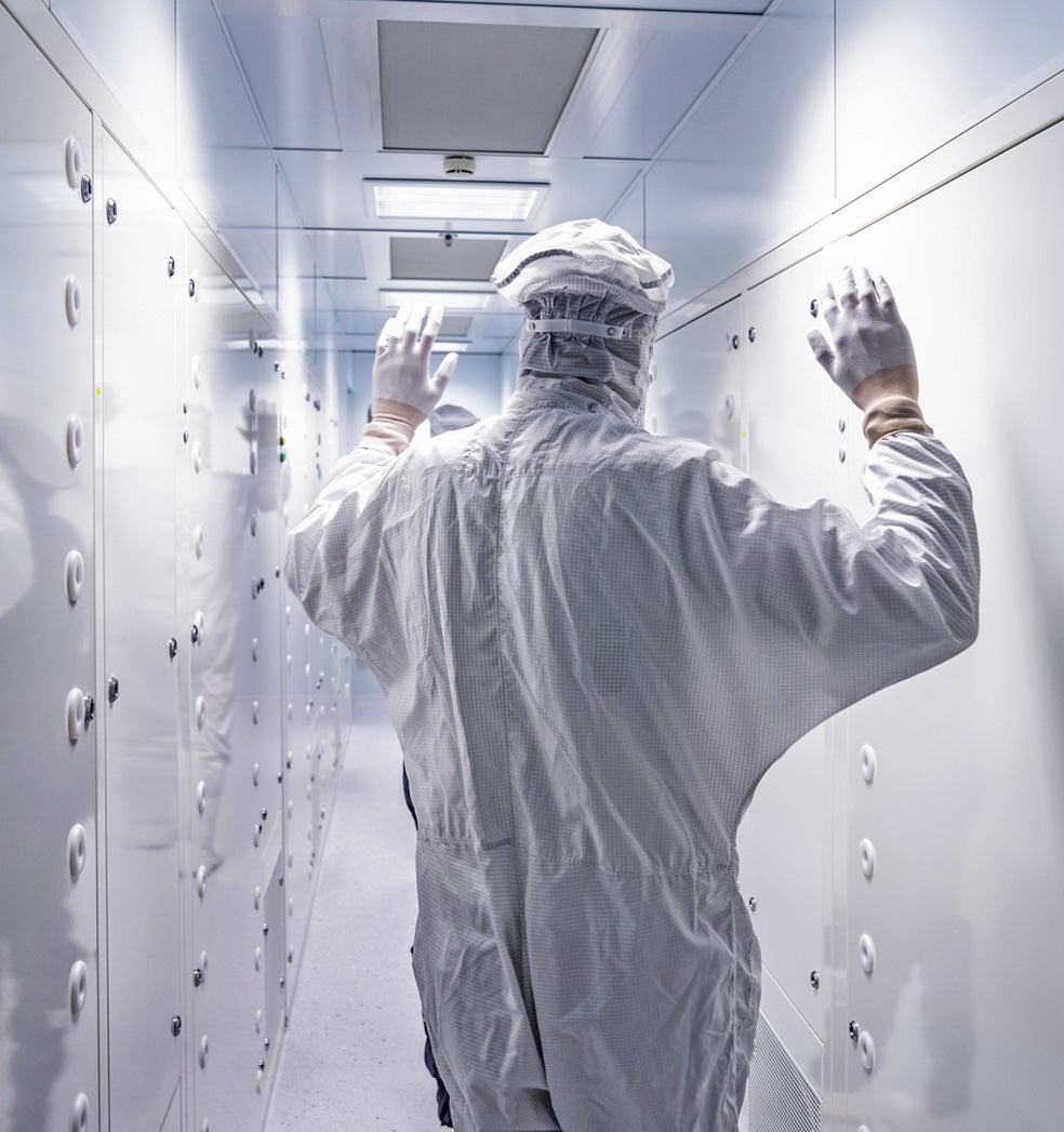 El grabado de los circuitos integrados puede verse afectado por la más mínima impureza, como una escama de piel. Por ello, quienes trabajan con ella van cubiertos por EPI. Más arriba, en la imagen que abre este reportaje, la máquina que imprime los minúsculos y laberínticos circuitos del chip. La holandesa ASML suministra máquinas como esta y controla el mercado mundial a partir de los 14 nanómetros de grosor (un cabello mide 60.000). Cobra 170 millones de euros por cada máquina.