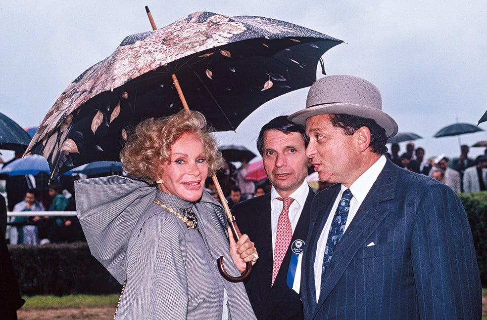 Los Wildenstein (el del sombrero es su marido, Alec) eran una de las familias más ricas y poderosas del mundo del arte con una actividad secundaria en la cría de caballos de carreras y un inventario de obras maestras que incluía dos Botticelli, ocho Rubens, ocho Rembrandt, cinco Tintorettos, tres Velázquez, nueve Grecos... Entonces, ella lucía vestidos de diseñadores como Karl Lagerfeld, creados para ella y valorados en 350.000 dólares, gastaban medio millón al año solo en vinos...