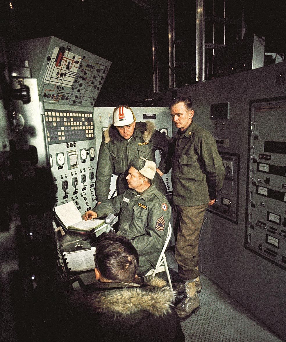 Varios especialistas, en 1962, observan el panel de control de Camp Century, la planta nuclear que se instaló en Groenlandia. A su lado, una de las escotillas de escape. La instalación sigue allí, bajo el hielo.