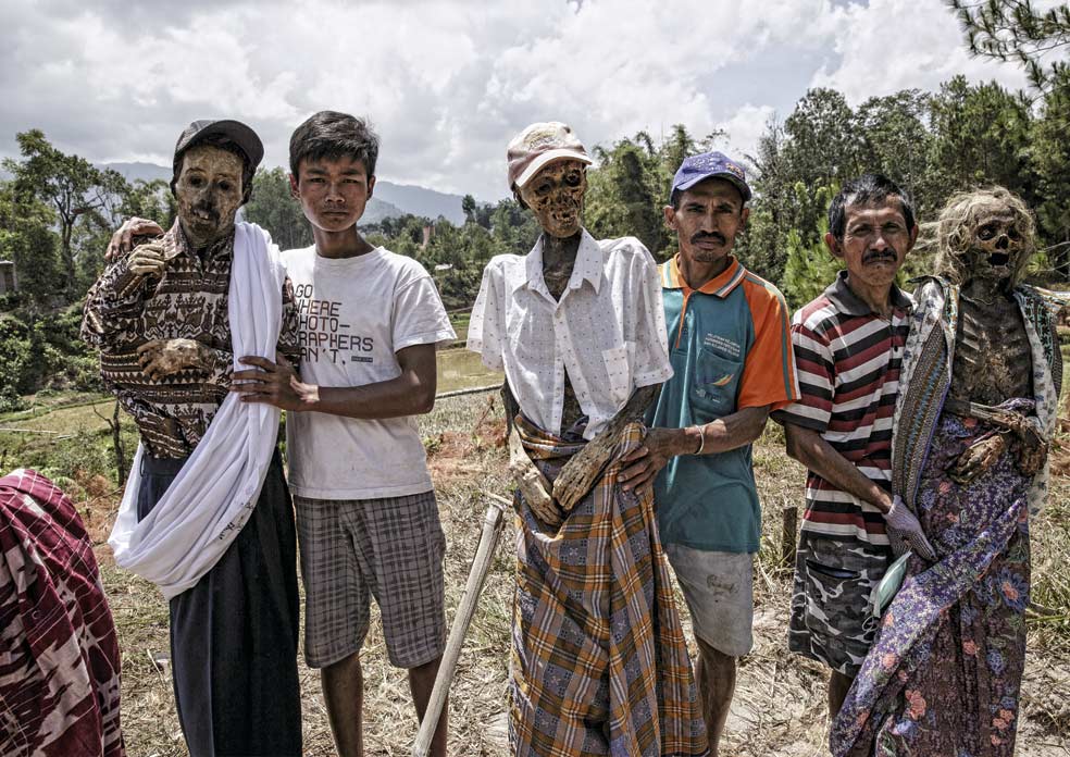 Varios toroyanos posan orgullosos con los cadáveres de sus parientes vestidos para la celebración de cada mes de agosto.