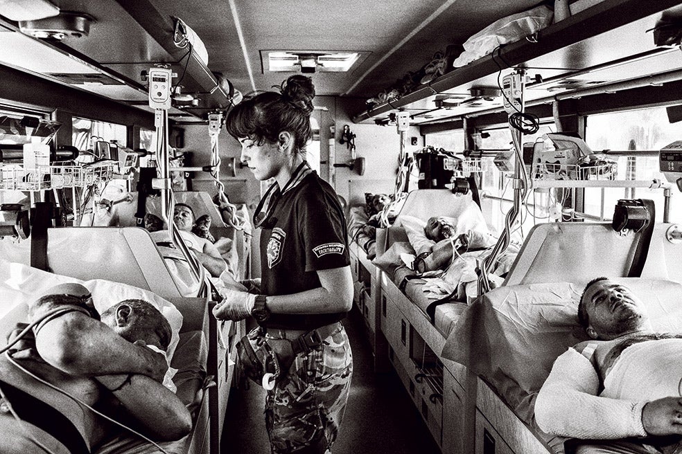 Trenes y autobuses medicalizados son el método más seguro para evacuar a los soldados ucranianos desde las zonas de guerra. A la izquierda: evacuación, en agosto de 2022, de heridos derrotados en la batalla de Pisky. En la imagen que abre este reportaje, más de 440 cadáveres enterrados en un bosque. Esto es lo que descubrieron las tropas ucranianas, en septiembre de 2022, tras la reconquista de Izium. Muchos cuerpos presentaban señales de tortura.