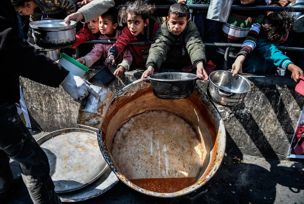 Niños palestinos acuden a por comida en una distribución de ayuda humanitaria en Rafah, pero los pucheros ya están vacíos. Hay zonas enteras del territorio de la franja donde la escasez de alimentos es total.