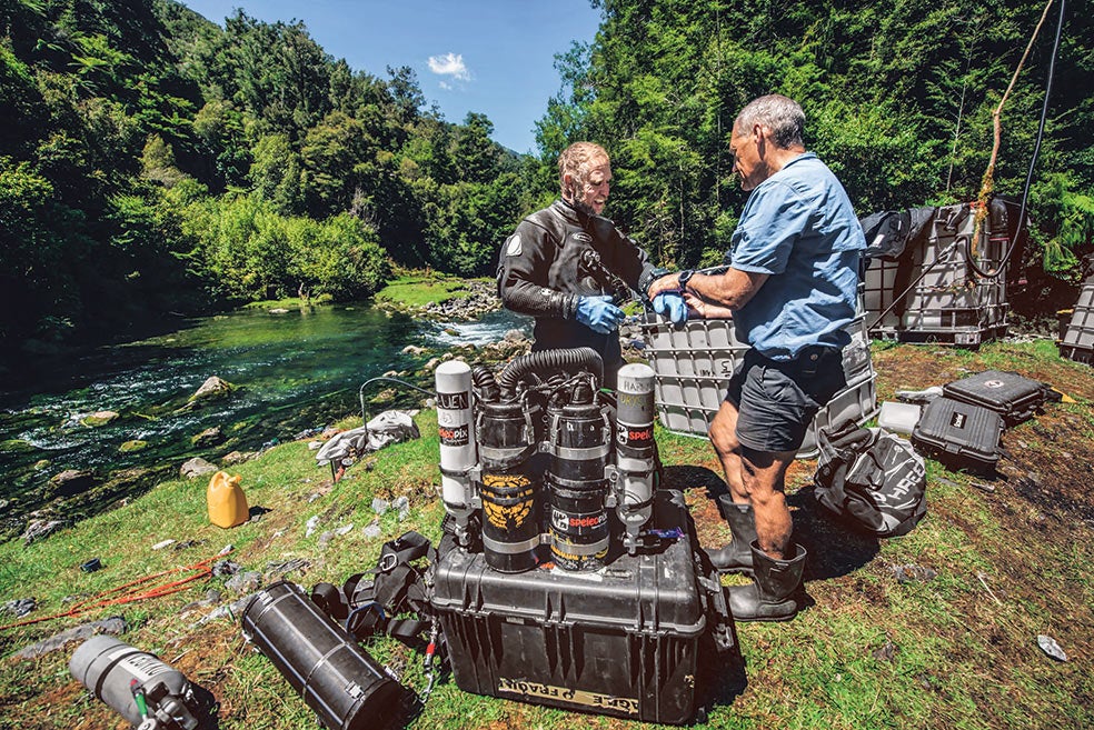 Los buceadores Richard Harris y Craig Challen con sus equipos de inmersión. Uno de ellos contiene una mezcla de oxígeno, helio e hidrógeno; y el otro, el estándar de oxígeno, helio y nitrógen. Más arriba, en la imagen que abre este reportaje, los dos expertos del buceo profundo en el arranque de la primera inmersión con hidrógeno en una inmensa cueva submarina en Nueva Zelanda.