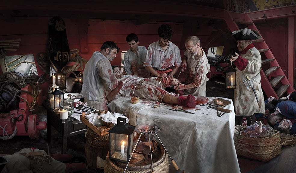 La enfermería estaba bajo la línea de flotación, pero en combate se subía al combés (zona de cubierta) para tener más luz. Esta imagen recrea la amputación de la pierna izquierda que sufrió Blas de Lezo a los 15 años cuando intentaba recuperar Gibraltar en 1704. El instrumental: sierra de arco, cuchillo curvo y hierros candentes. La anestesia: un cuero para morder. El coraje de Blas de Lezo lo dejó cojo, tuerto y manco a los 23 años.