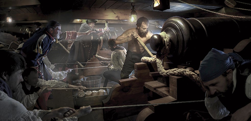 Poca luz, estrechez (apenas se cabía de pie), calor asfixiante y máximo peligro. Así se vivía en las baterías. El cabo artillero daba las órdenes para cargar los cañones (el de la foto, de cuatro toneladas), para posicionarlos en las portas, moverlos con cuñas y espeques (palos) para apuntar y luego limpiarlos de pólvora y volver a empezar. El riesgo era extremo: podía derramarse pólvora e incendiarlo todo. Además, había que estar a (al menos) 400 metros del barco enemigo para disparar con tino. En la imagen que abre este reportaje, una tripulación en plena reparación del león engallado que como mascarón de proa coronaba los barcos de guerra de la Armada española del siglo XVIII. Jordi Bru crea estas imágenes utilizando réplicas de barcos, maquetas, figurantes que participan de las en recreaciones históricas y 'la magia' del Photoshop.