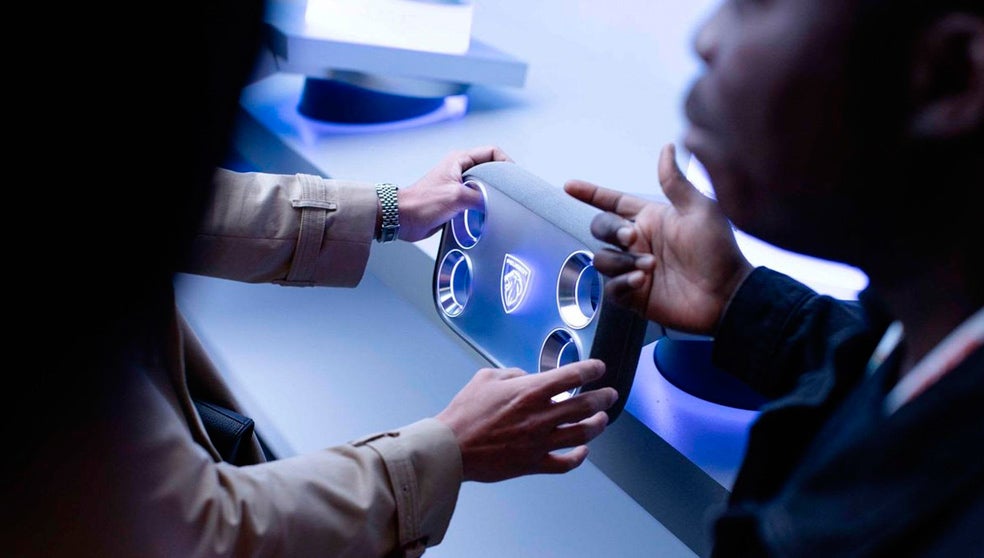 Si algo define la interacción tradicional entre conductor y vehículo es el volante. Peugeot se inspira en los videojuegos para reinterpretarlo con un mando rectangular sin conexiones físicas. Sus cuatro esquinas táctiles permiten controlar múltiples funciones con toques del pulgar.