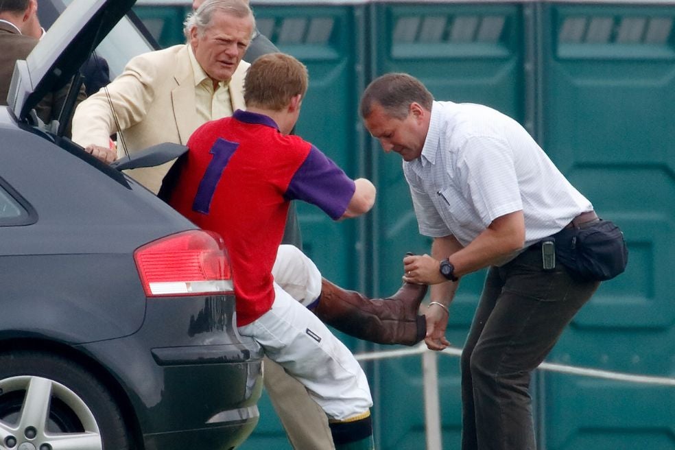 Un asistente ayuda con las botas a Enrique. «El personal bromea sobre sus despistes diciendo que, sin un sirviente, Harry tardaría semanas en ponerse los pantalones».
