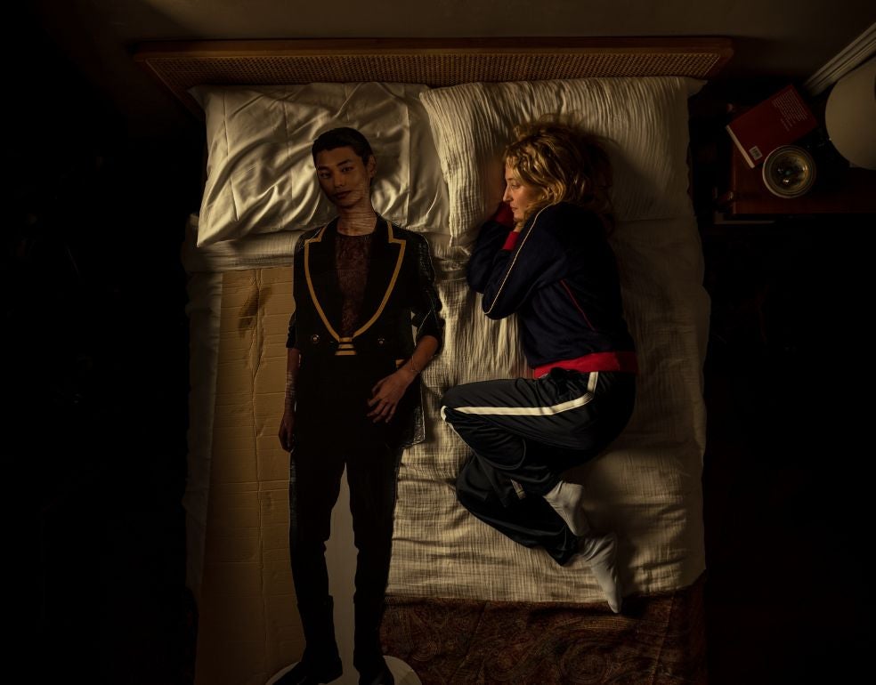 Alba Rohrwacher, en otra secuencia de Tres adioses, inspirada en el último libro –escrito antes de morir, en 2023– de la escritora italiana Michela Murgia. En la imagen, el personaje de Marta se tumba en su cama junto a Jirko, el cantante de K-pop (representado a tamaño natural en una silueta de cartón) al que ella le comenta lo que va sintiendo y pensando.